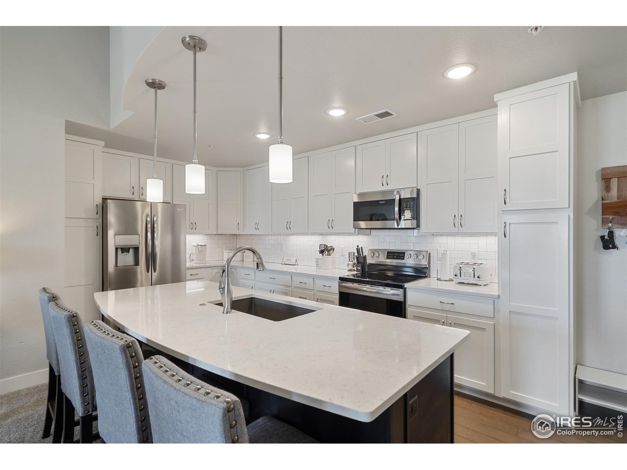 Gorgeous kitchen features Quartz counters, stainless steel appliances (all stay), dual pantry spaces, composite undermount sink, tile backsplash, and large island with bar!