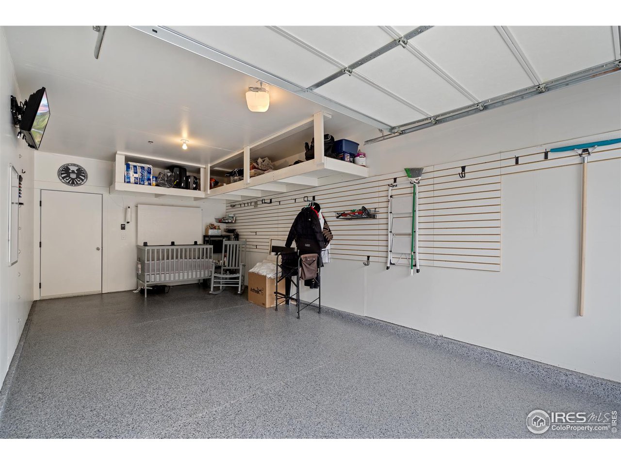 Oversized garage with epoxy floors, wall-mounted TV (included), racks and rail system